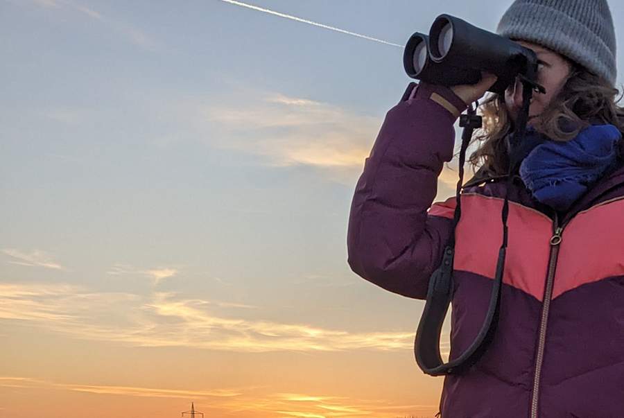 Frau mit Fernglas in der Dämmerung